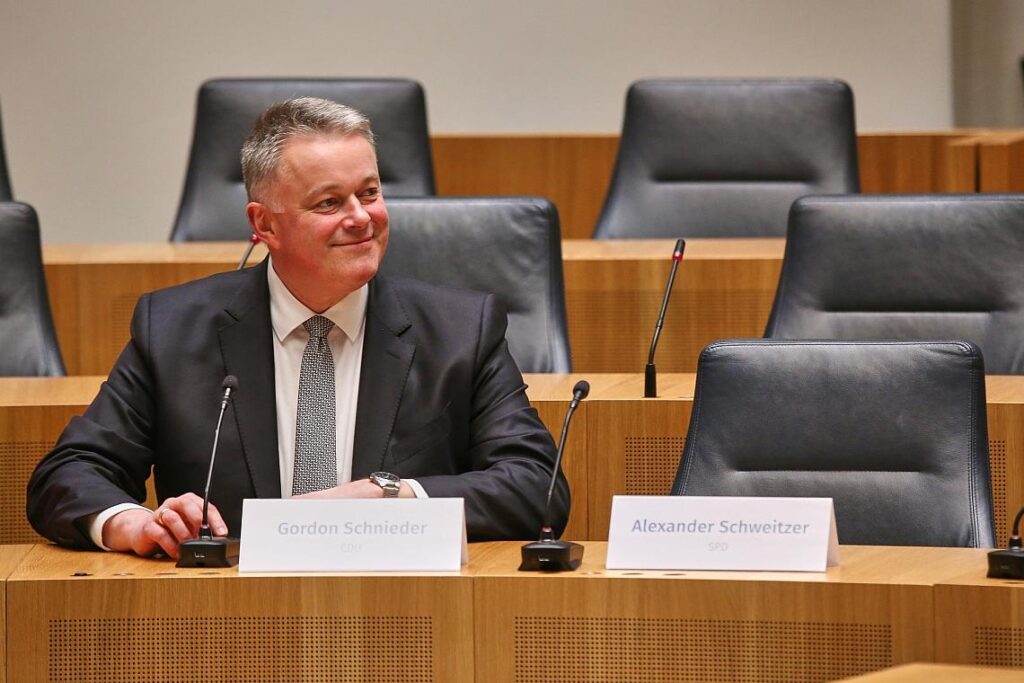 Gordon Schnieder sitzt neben dem leeren Stuhl von Alexander Schweitzer am 22.03.2026