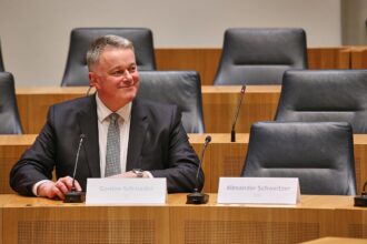 Gordon Schnieder sitzt neben dem leeren Stuhl von Alexander Schweitzer am 22.03.2026