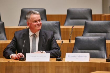 Gordon Schnieder sitzt neben dem leeren Stuhl von Alexander Schweitzer am 22.03.2026