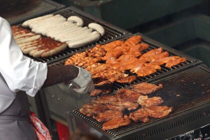 Hähnchenschnitzel und Würste auf einem Grill (Archiv)